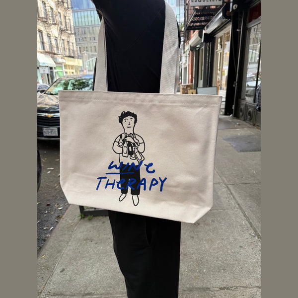 Wine Therapy NYC cream canvas tote bag featuring black cartoon figure holding wine bottles